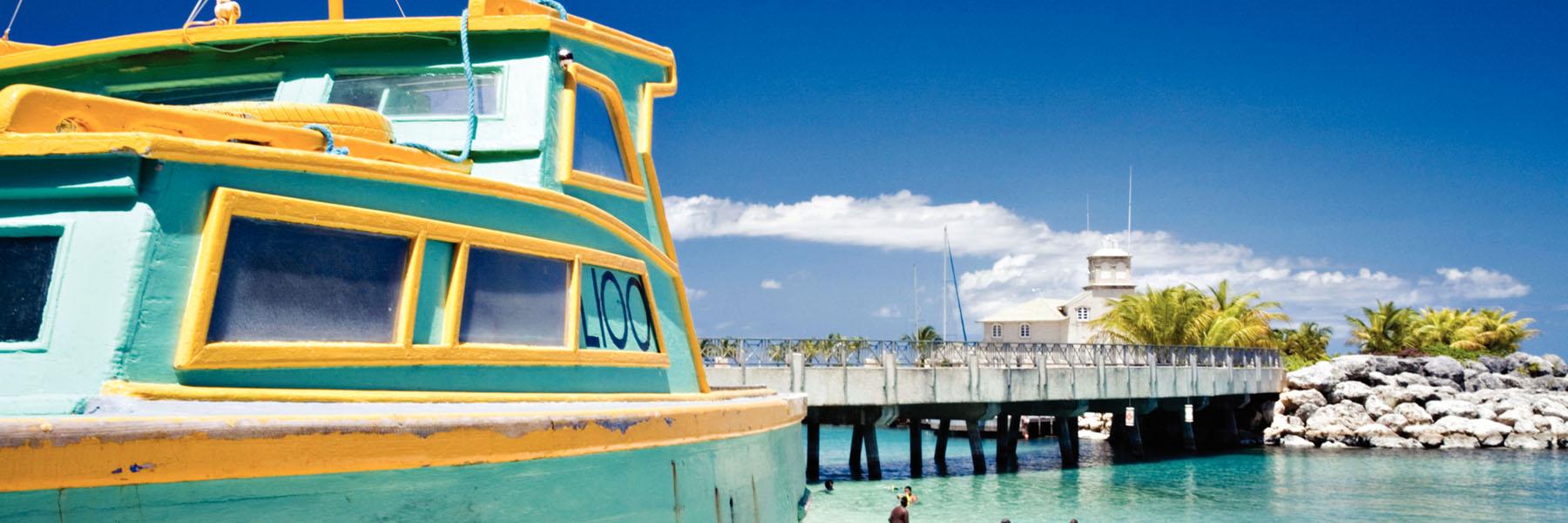 Vibrant fishing boat and coastal jetty in Barbados, a popular UK winter sun getaway.
