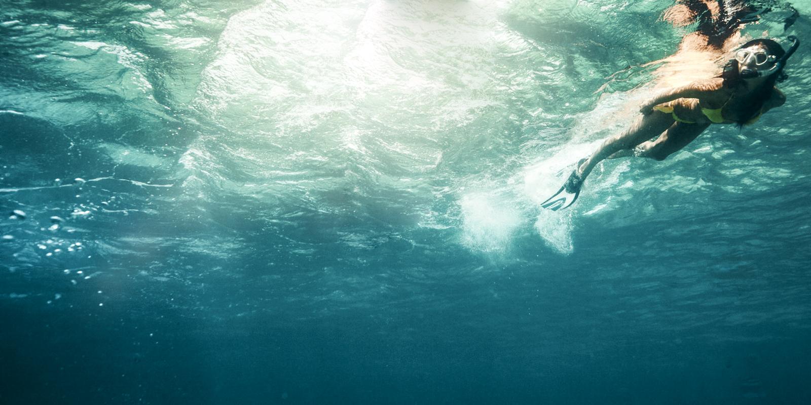Snorkeller swimming underwater in clear turquoise sea off Antigua, a top winter sun destination from the UK.