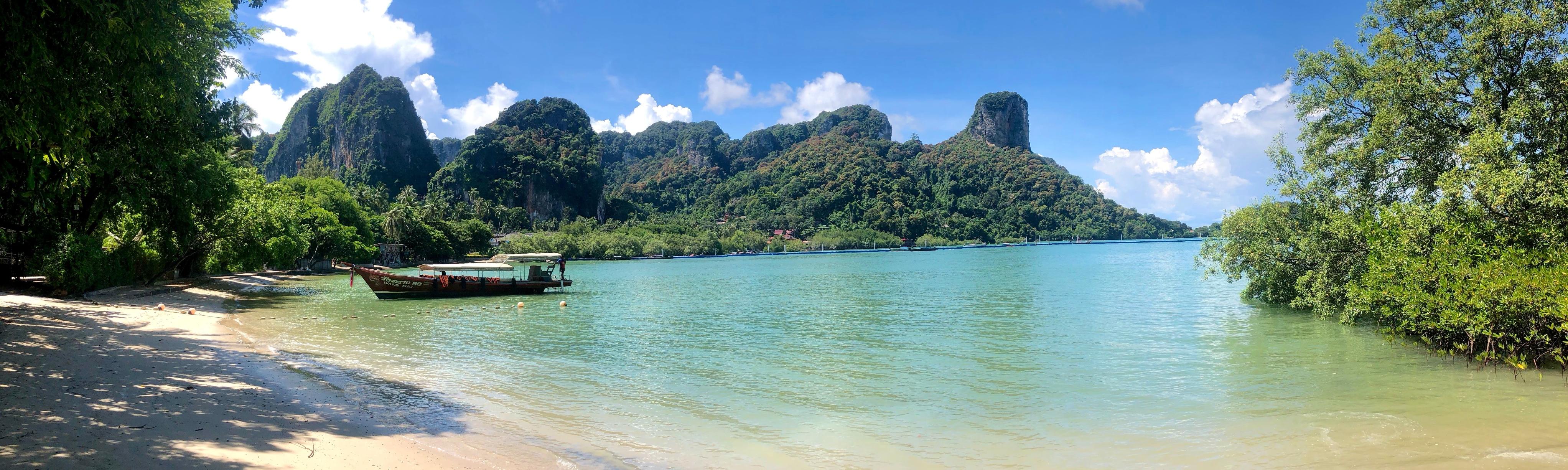 Traditional longtail boat on Railay Beach beneath limestone cliffs in Thailand — where to go in August beyond Europe.