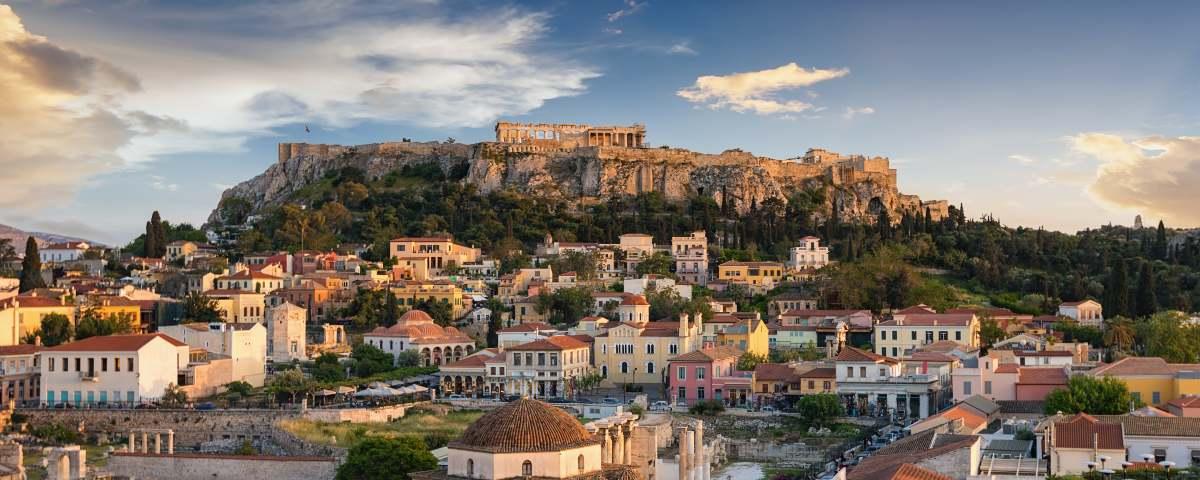 The ancient Greek Parthenon on top of the Athens Acropolis, with city buildings and more archaeological sites in the foreground. It's an exciting city to visit with children.