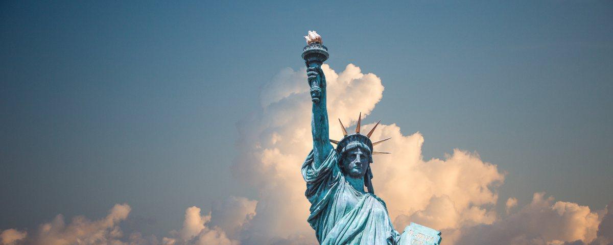 New York's iconic Statue of Liberty holding her torch proudly against a blue sky with dramatic clouds