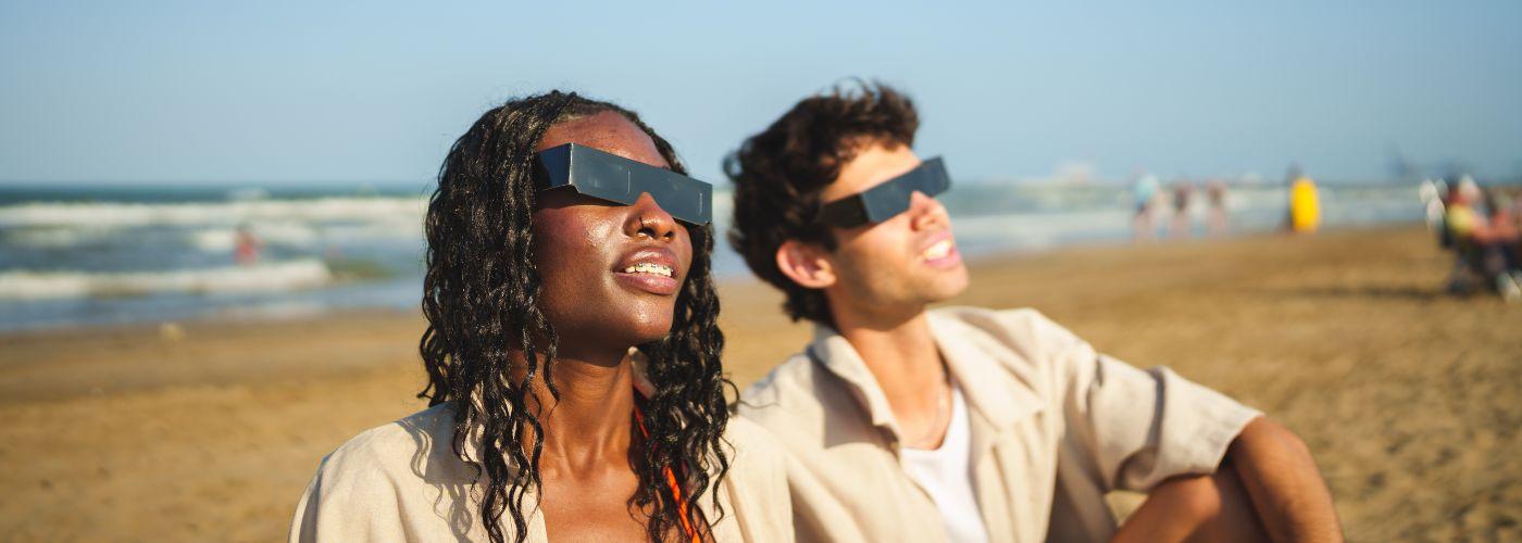 A couple, wearing solar viewers, looking towards the sun