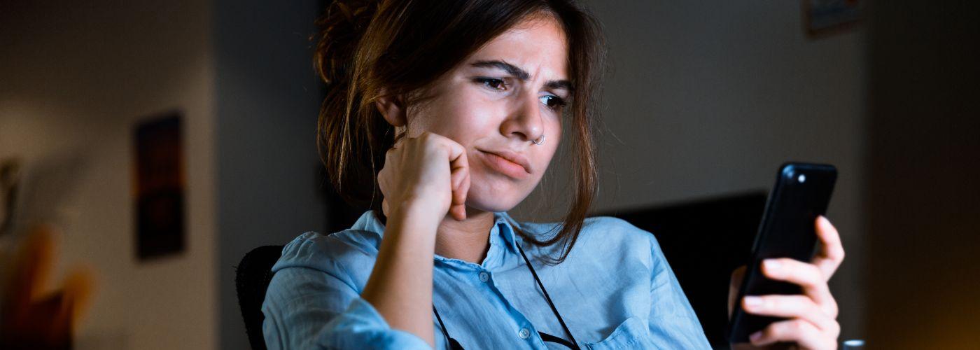 Woman looking at phone with an unsure look