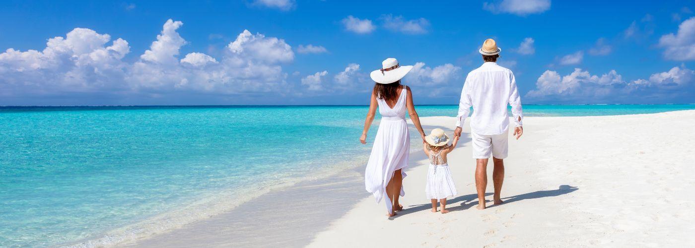 Parents take daughter along the white sandy beach in the Maldives