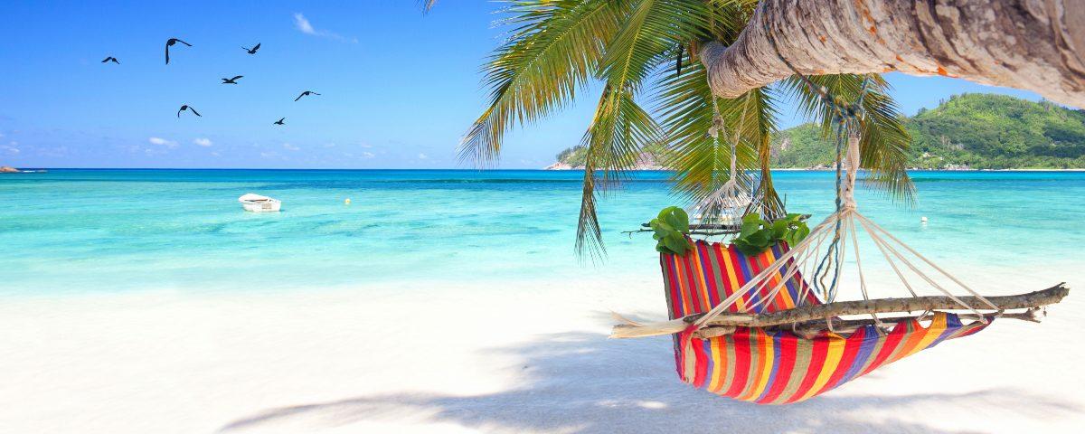 An inviting stripy hammock on a tropical white sand beach