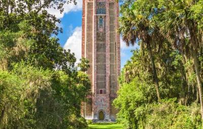 View across the water in the lush Bok Tower Gardens to the red brick tower, famous for its tuneful bells