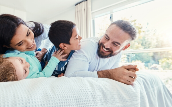 A smiling family of four playing in their relaxing family room on holiday