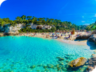 Turquoise cove beach with cliffs and pine trees – perfect for September holidays.