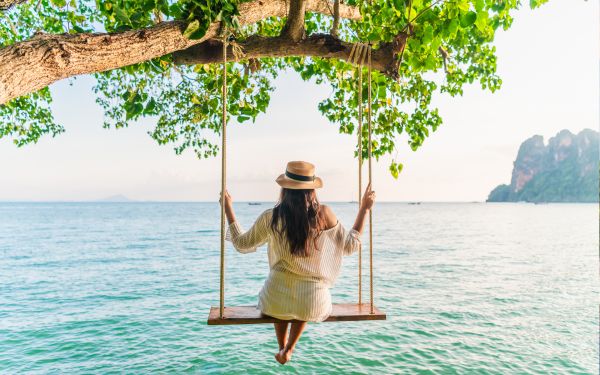 Woman on a swing over the sea in Thailand 
